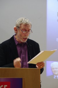 Michael Rosen standing at the lectern talking with impassioned gestures.
