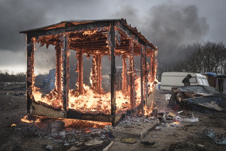 Calais, France. 05/03/16. A shelter built by the French organisation Medecin Sans Frontieres (Doctors Without Borders) burns in the Calais 'Jungle'. French authorities are demolishing the southern half of the camp, which charities estimate to contain 3,500 people.