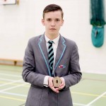 Reece is pictured in his school sports hall, wearing his uniform, holding his Keepsake, a Tibetan amulet box.