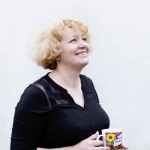 Anna looks upwards smiling towards the sky, holding her Ukrainian mug.